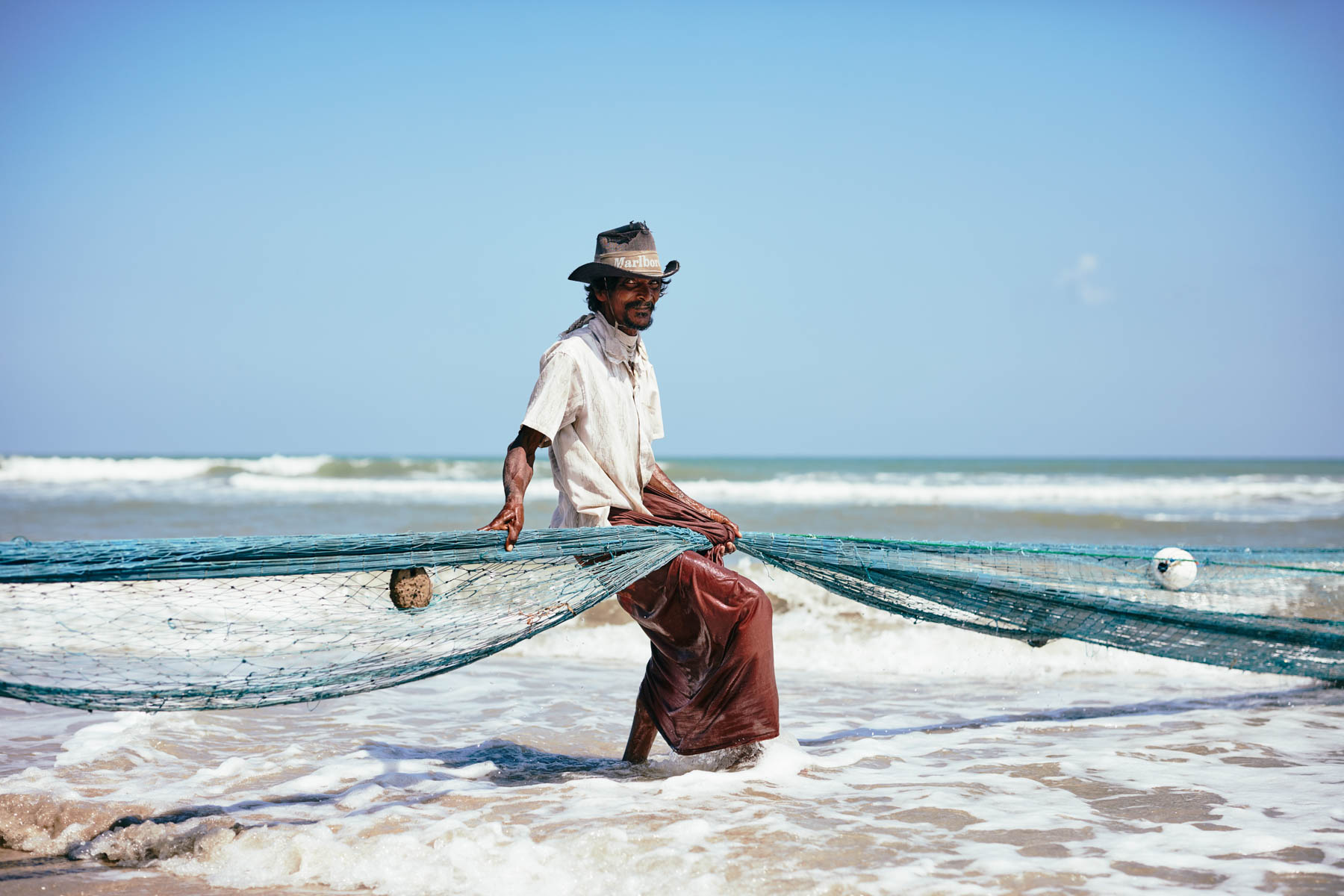 Portrait von einem Fischer mit Hut beim Netz einholen in Trincomalee/ Sri Lanka, 2019