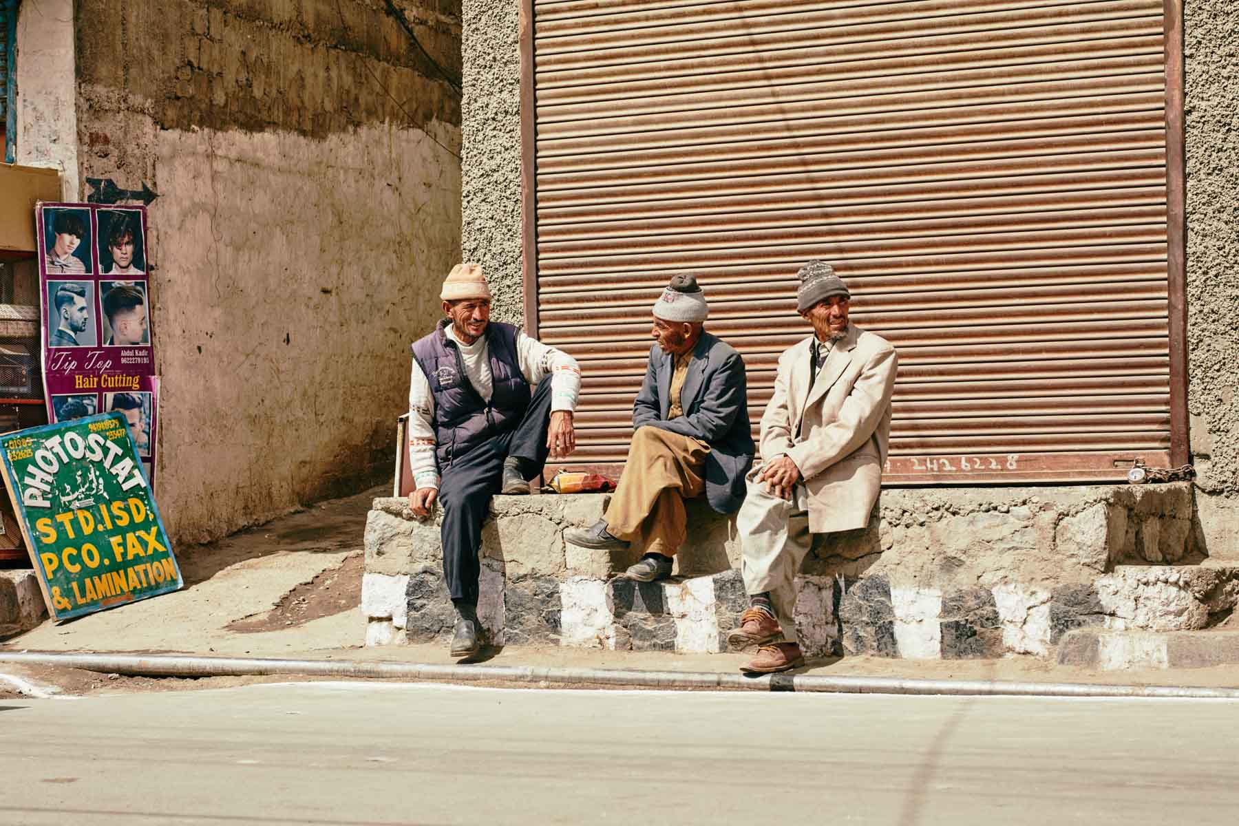 Drei am Straßenrand sitzende Männer in Kargil/ Ladakh/ Indien, 2018